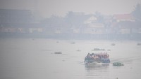 Sejumlah pelajar berangkat sekolah menggunakan perahu tradisional melewati kawasan yang diselimuti kabut asap di Sungai Ogan, Palembang, Sumatera Selatan, Sabtu (30/9/2023). 