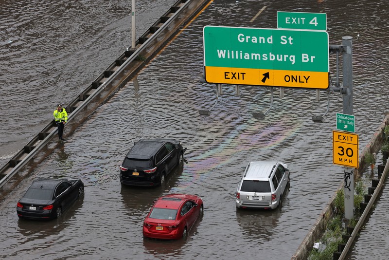 A police officer stands as he assists motorists stuck on a flooded street after heavy rains as the remnants of Tropical Storm Ophelia bring flooding across the mid-Atlantic and Northeast, at the FDR Drive in Manhattan near the Williamsburg Bridge, in New York City, U.S., September 29, 2023.  REUTERS/Andrew Kelly