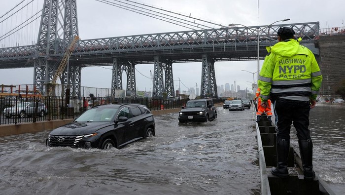 A police officer from the NYPD Highway Patrol looks to motorists drive through a flooded street after heavy rains as the remnants of Tropical Storm Ophelia bring flooding across the mid-Atlantic and Northeast, at the FDR Drive in Manhattan near the Williamsburg Bridge, in New York City, U.S., September 29, 2023.  REUTERS/Andrew Kelly     TPX IMAGES OF THE DAY