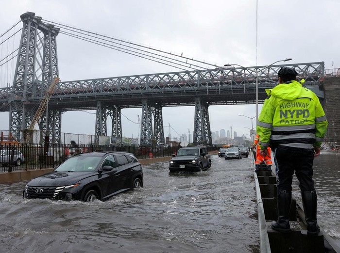 A police officer from the NYPD Highway Patrol looks to motorists drive through a flooded street after heavy rains as the remnants of Tropical Storm Ophelia bring flooding across the mid-Atlantic and Northeast, at the FDR Drive in Manhattan near the Williamsburg Bridge, in New York City, U.S., September 29, 2023.  REUTERS/Andrew Kelly     TPX IMAGES OF THE DAY