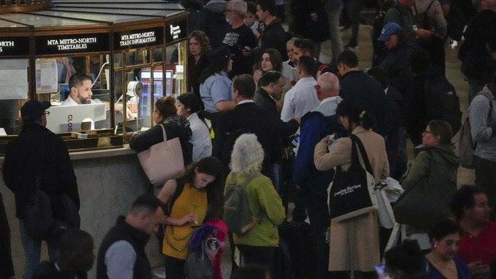 Commuters stand on a track around the closed doors of a train they thought would run on the Hudson River line at Grand Central Terminal, Friday, Sept. 29, 2023, in New York. The train was not in service due to heavy rains in the area. (AP Photo/Mary Altaffer)