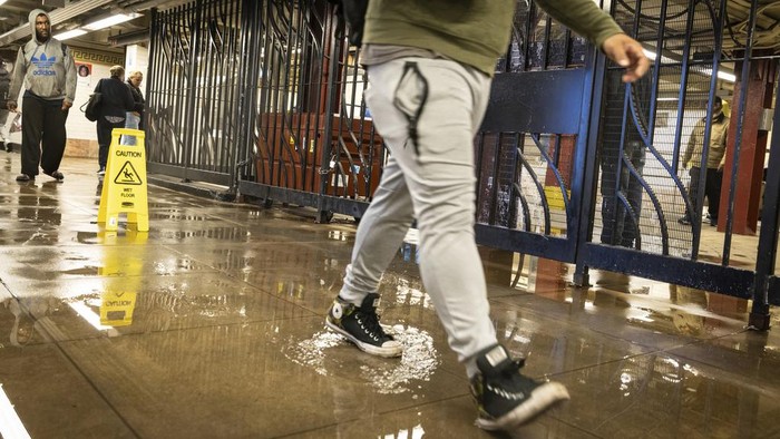 A commuter walking through a large puddle at the entrance of the Bowery Subway station following heavy rains in the Lower East Side, Manhattan on Friday, Sept. 29, 2023, in New York. (AP Photo/Stefan Jeremiah)