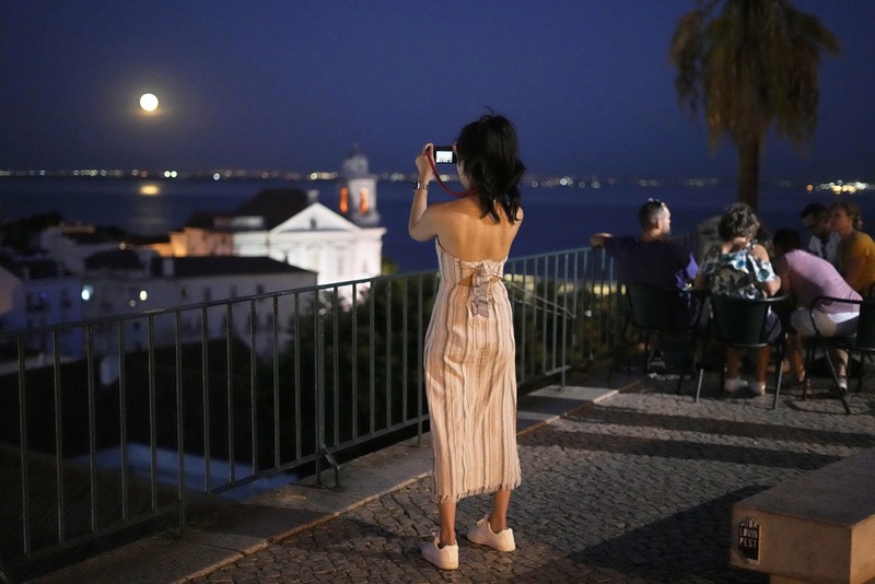An exhaust pipe from a diesel generator spouts fumes as the September full moon, known as the Harvest Moon, rises in the background, in Beirut, Lebanon, Friday, Sept. 29, 2023. (AP Photo/Hassan Ammar)
