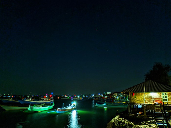 Pemandangan di tepi dermaga dengan lampu-lampu perahu milik nelayan Desa Pulau Maringkik, Lombok Timur, yang berkedip. (Ahmad Viqi)