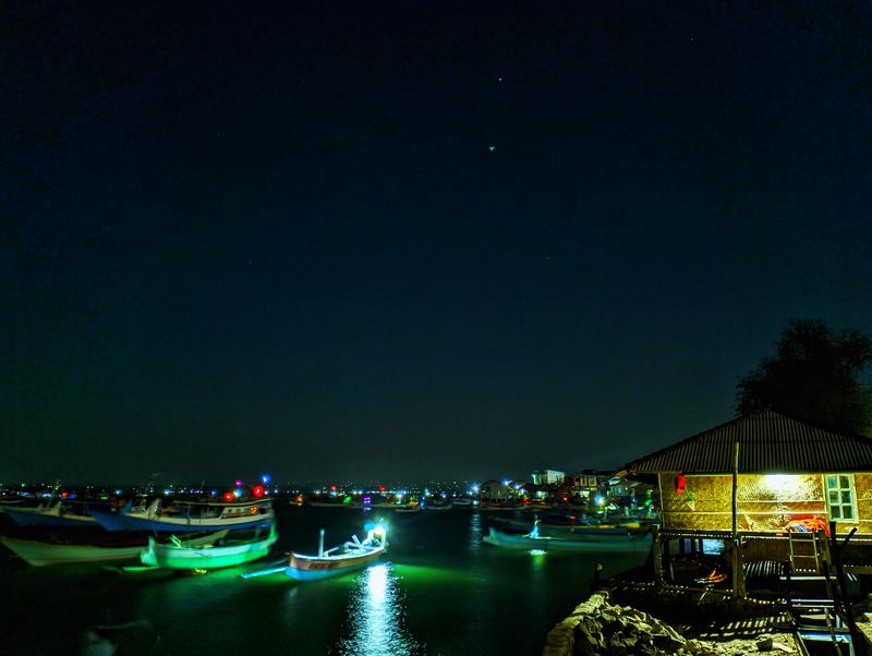 Pemandangan di tepi dermaga dengan lampu-lampu perahu milik nelayan Desa Pulau Maringkik, Lombok Timur, yang berkedip. (Ahmad Viqi)