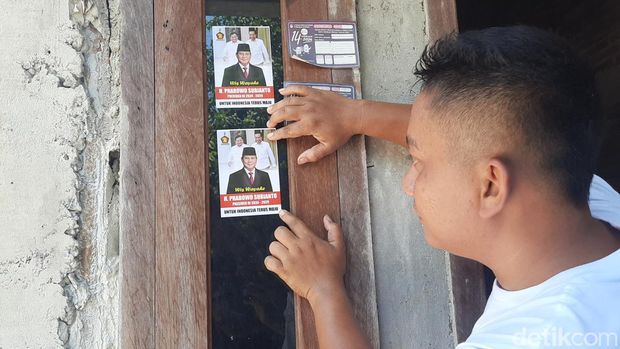 Relawan menempelkan stiker bergambar Prabowo dan Jokowi di rumah warga Pati, Minggu (1/10/2023).