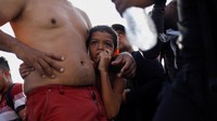 Anak migran Venezuela Hendry Rico, 9, berpegangan pada pinggang ayahnya sambil menyaksikan migran lain berjalan melalui sungai Rio Grande.  
