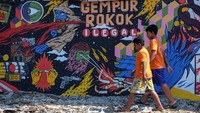 Warga melewati mural bertema Gempur Rokok Ilegal di Solo, Jawa Tengah, Senin (2/10/2023).