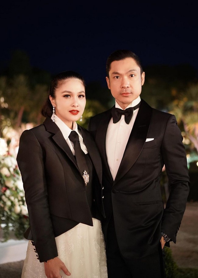 Ibu dua anak ini memakai bustier berbahan scuba yang dipadu blazer hitam rancangan desainer Cynthia Tan. Busana atasannya dipadankan dengan rok panjang berhias bordir. Dasi hadir sebagai pelengkap penampilan. Foto: Instagram/@sandradewi88