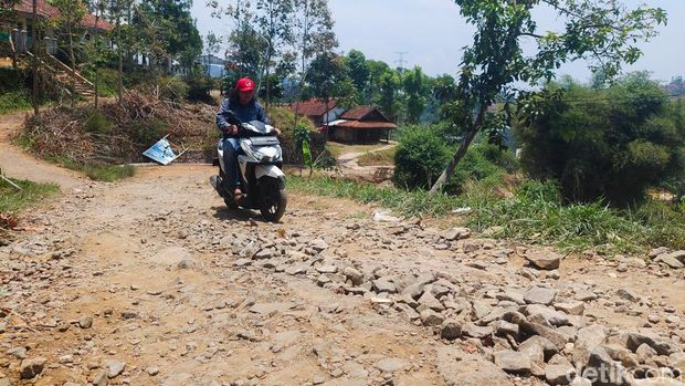 Warga Melintasi Jalan Karyamukti yang Rusak Parah