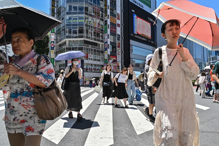 This photo taken on July 30, 2023 shows people using umbrellas and parasols to seek relief from the heat while crossing a street in Tokyo, as temperatures of 35C-plus (95F) have scorched the Japanese capital for weeks. (Photo by Richard A. Brooks / AFP)