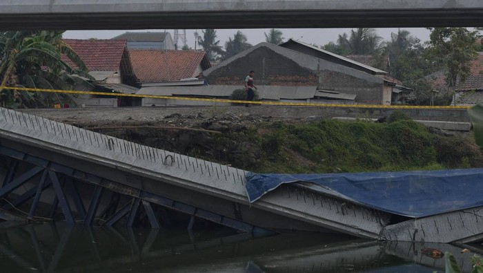 Konstruksi jembatan penghubung roboh di Cikarang Timur Seorang warga melintas di samping konstruksi jembatan penghubung ke kawasan industri Jababeka yang roboh di Jalan Raya Citarik, Desa Jatireja, Cikarang Timur, Kabupaten Bekasi, Jawa Barat, Senin (2/10/2023). Menurut penuturan warga jembatan roboh pada 11.30 WIB menyebabkan dua pekerja terluka dan penyebab kejadian masih dalam penyelidikan pihak terkait. ANTARA FOTO/ Fakhri Hermansyah/hp.