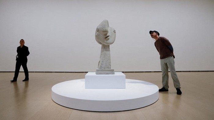 Visitors observe a sculpture at the exhibition 