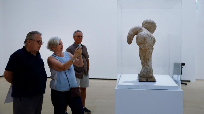 Visitors observe a sculpture at the exhibition 