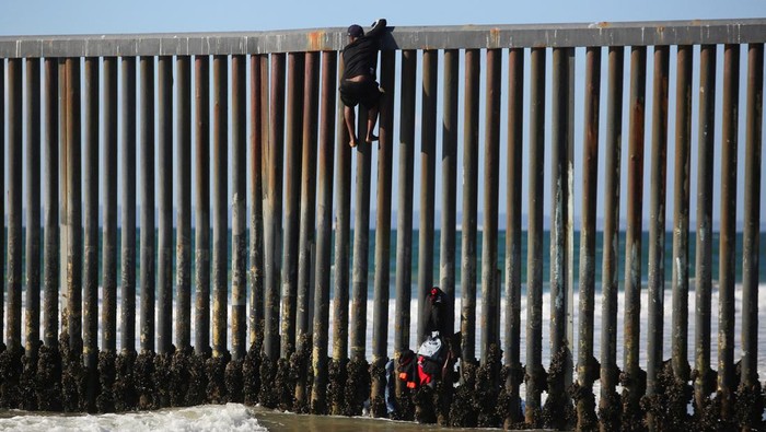 A migrant climbs the border fence to cross into the U.S. to request asylum, at Playas de Tijuana, in Tijuana, Mexico October 2, 2023. REUTERS/Jorge Duenes