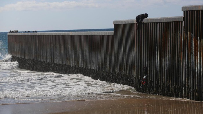 A migrant climbs the border fence to cross into the U.S. to request asylum, at Playas de Tijuana, in Tijuana, Mexico October 2, 2023. REUTERS/Jorge Duenes