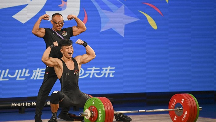 Lifter putra Indonesia Rahmat Erwin Abdullah (bawah) berpose dengan pelatih sekaligus ayahnya Erwin Abdullah (atas) usai melakukan angkatan clean and jerk pada final 73 kilogram Grup A Asian Games 2022 di Xiaoshan Sports Centre Gymnasium, Hangzhou, China, Selasa (3/10/2023). Rahmat Erwin meraih medali emas dengan total angkatan 359 kilogram sekaligus memecahkan rekor Asian Games, sementara untuk angkatan clean and jerk Rahmat berhasil memecahkan rekor dunia dengan total angkatan 201 kilogram. ANTARA FOTO/M Risyal Hidayat/rwa.