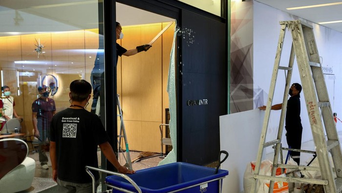 Workers repair the glass door of a furniture store where a teenage gunman was arrested last night inside the luxury Siam Paragon shopping mall after killing foreigners and wounding other people in a shooting, in Bangkok, Thailand, October 4, 2023. REUTERS/Athit Perawongmetha