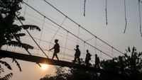 Pelajar SD melintas di jembatan gantung yang kondisinya rusak dan memprihatinkan di Desa Parungkujang, Lebak, Banten, Rabu (4/10/2023). Jembatan gantung yang menjadi akses utama masyarakat di desa itu lantai jembatannya telah keropos dan beberapa tali seling putus.