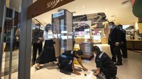 Anggota staf Siam Paragon Mall memeriksa kabel detektor logam sebelum membuka mal. Stasiun televisi lokal PBS melaporkan korban luka mencapai lima orang.