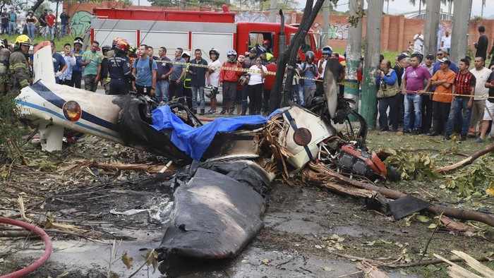 Residents looks at the wreckage of a Colombian Air Force aircraft that crashed into an urban area of Cali, Colombia, Tuesday, Oct. 3, 2023. According to authorities, one person on board died and another survived. (AP Photo/Juan B. Diaz)