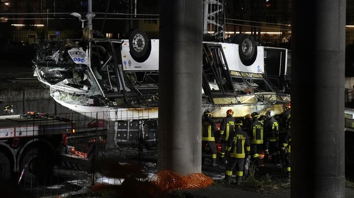 Tragis! Bus di Italia Terjun dari Jembatan, 20 Orang Tewas Italian firefighters work at the scene of a passenger bus accident in Mestre, near Venice, Italy, Wednesday, Oct. 4, 2023. According to local media, the bus fell a few meters from an elevated rod before crashing Tuesday close to Mestre's railway tracks, where it caught fire. (AP Photo/Antonio Calanni)