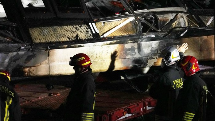 Tragis! Bus di Italia Terjun dari Jembatan, 20 Orang Tewas Italian firefighters work at the scene of a passenger bus accident in Mestre, near Venice, Italy, Wednesday, Oct. 4, 2023. According to local media, the bus fell a few meters from an elevated rod before crashing Tuesday close to Mestre's railway tracks, where it caught fire. (AP Photo/Antonio Calanni)