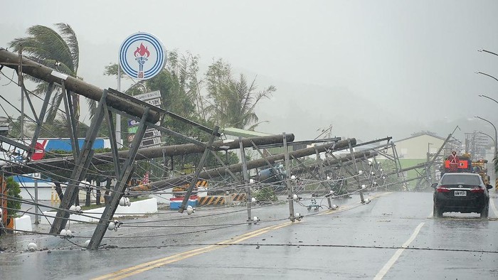 A car passes by power lines downed by the high winds from Typhoon Koinu in Taiwans southern Pingtung County on October 5, 2023. Typhoon Koinu grazed the southern edge of Taiwan on October 5, blanketing the region in torrential rain and bringing record-breaking winds of more than 340 kilometres an hour to an outlying island. (Photo by Sean CHANG / AFP)