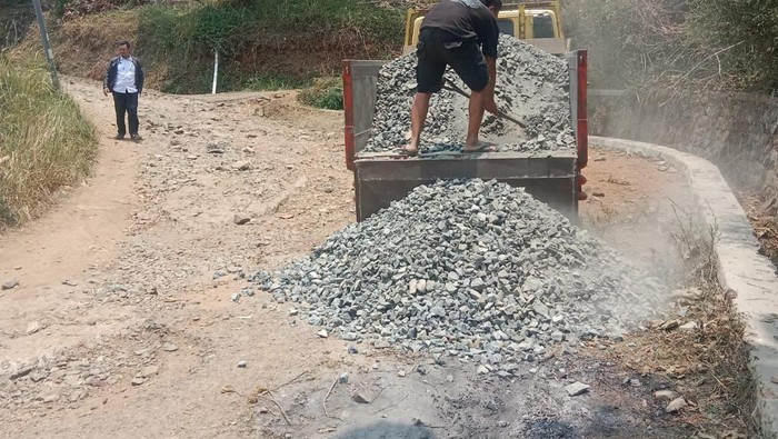 Pekerja Menurunkan Material Perbaikan Jalan Karyamukti