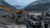 Alat berat seperti ekskavator dikerahkan untuk mengevakusi truk yang terkubur lumpur banjir.  