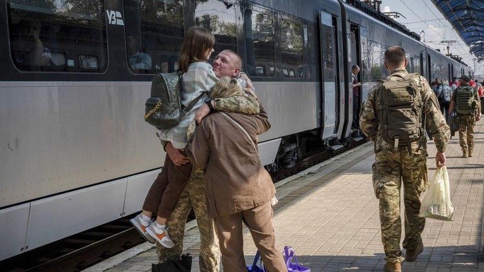 Sibuknya Kereta Ukraina, Jalur Penghubung Ibu Kota-Medan Perang A Ukrainian serviceman hugs his wife and the daughter at the railway station in Sloviansk, Donetsk region, Ukraine on Tuesday, Sept. 12, 2023. The train that runs from Ukraine's capital, Kyiv, to the city of Kramatorsk in the east stands apart from others in Ukraine. It is shrouded in solemn silence as passengers anticipate their final destination β in front-line areas where battles rage between Ukrainian and Russian forces. (AP Photo/Hanna Arhirova)