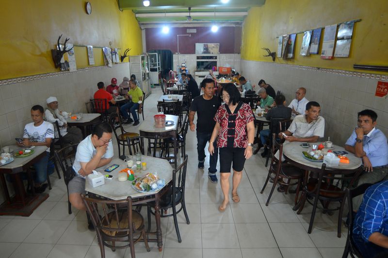 Pengunjung menikmati sate Padang berbareng es kopi di Warung Kopi (Warkop) Nan Yo, di Pondok, Padang, Sumatera Barat, Kamis (5/10/2023). Warkop legendaris nan berdiri sejak 1932 itu menyajikan kopi robusta nan diseduh style Hainan dengan nuansa warung ala era dulu namun tetap dikunjungi konsumen dari beragam usia. ANTARA FOTO/Iggoy el Fitra/tom.