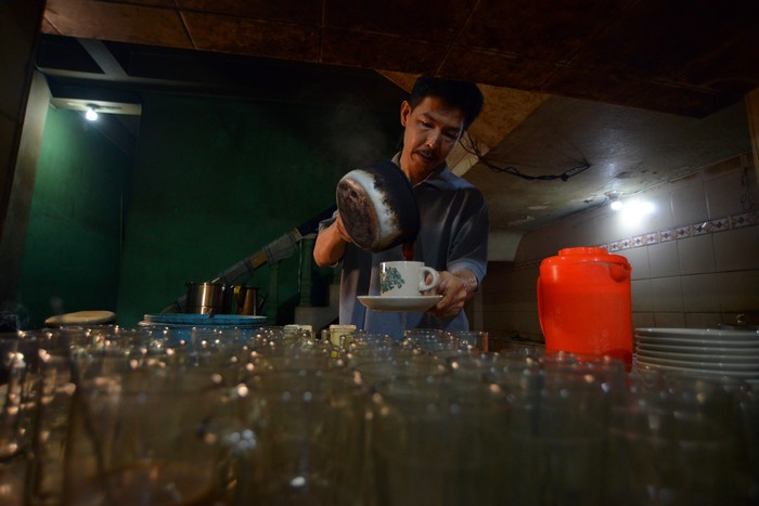 Pengunjung menikmati sate Padang bersama es kopi di Warung Kopi (Warkop) Nan Yo, di Pondok, Padang, Sumatera Barat, Kamis (5/10/2023). Warkop legendaris yang berdiri sejak 1932 itu menyajikan kopi robusta yang diseduh gaya Hainan dengan nuansa warung ala zaman dulu namun tetap dikunjungi konsumen dari berbagai usia. ANTARA FOTO/Iggoy el Fitra/tom.