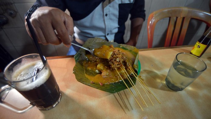 Pengunjung menikmati sate Padang bersama es kopi di Warung Kopi (Warkop) Nan Yo, di Pondok, Padang, Sumatera Barat, Kamis (5/10/2023). Warkop legendaris yang berdiri sejak 1932 itu menyajikan kopi robusta yang diseduh gaya Hainan dengan nuansa warung ala zaman dulu namun tetap dikunjungi konsumen dari berbagai usia. ANTARA FOTO/Iggoy el Fitra/tom.