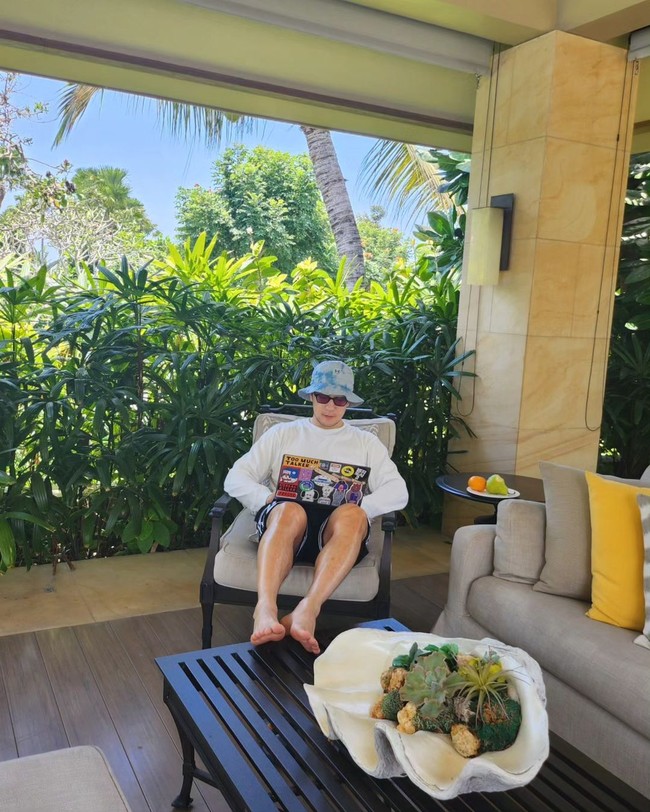 Foto lain menampilkan Son Sukku selonjoran di kursi hotel dan menaikkan kaki ke atas meja. Sang aktor menggambarkan suasana nyata WFB alias Work From Bali. Foto: dok. Instagram @sonsukku