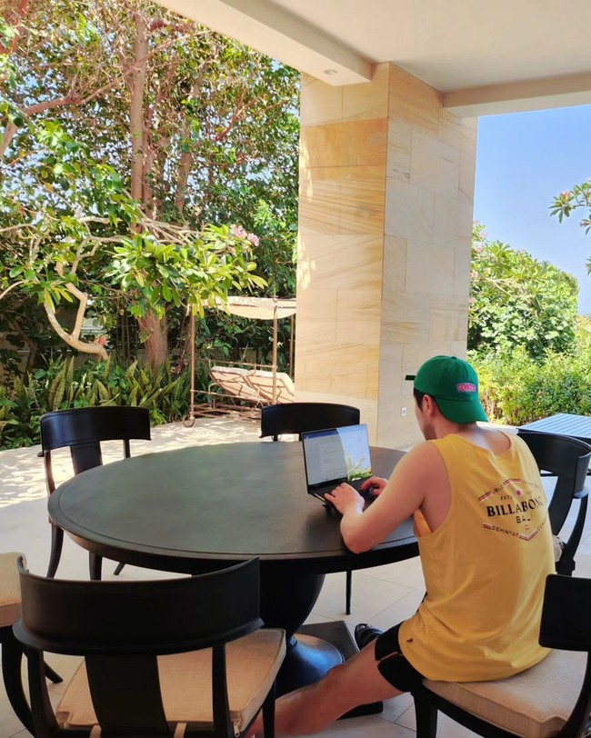 Sejumlah penggemar Indonesia menyebut Son Sukku sudah melokal. Dia tampak bekerja di depan laptopnya memakai kaos kutang berwarna kuning yang dibeli di gerai Billabong Seminyak dan beralas kaki sendal. Foto: dok. Instagram @sonsukku