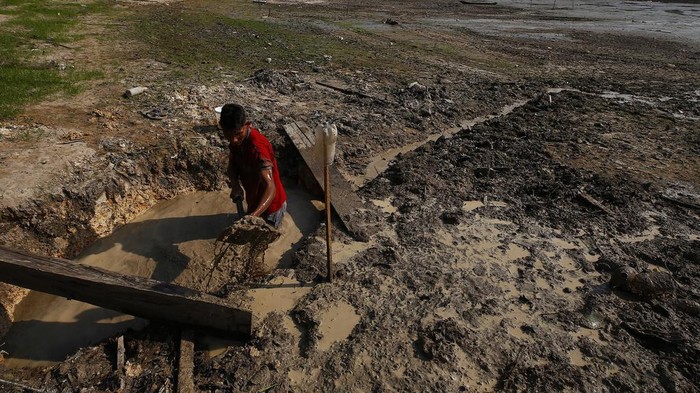 Isac Cicero Rodrigues digs into the dry bed of Puraquequara lake to obtain water amid a severe drought, in Manaus, Amazonas state, Brazil, Thursday, Oct. 5, 2023. The Brazilian Amazon rainforest is facing a severe drought that may affect around 500,000 people by the end of the year. (AP Photo/Edmar Barros)