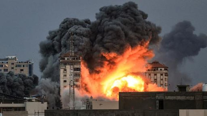 EDITORS NOTE: Graphic content / People standing on a rooftop watch as a ball of fire and smoke rises above a building in Gaza City on October 7, 2023 during an Israeli air strike. At least 70 people were reported killed in Israel, while Gaza authorities released a death toll of 198 in the bloodiest escalation in the wider conflict since May 2021, with hundreds more wounded on both sides. (Photo by MAHMUD HAMS / AFP)