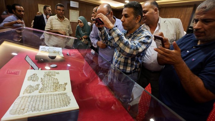 Visitors take photos of a restored rare copy of the holy Koran, which is considered to be one of the world's oldest copies of the holy book and dates back to the first Hijri century, according to Egypt's National Library and Archives, at Egypt's National Library and Archives, in Cairo, Egypt September 27, 2023. REUTERS/Mohamed Abd El Ghany