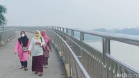 Ibu-ibu terlihat mengenakan masker saat berjalan di jembatan terpanjang Gentala Arasy (Foto: Ferdi Al Munanda)