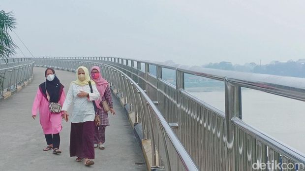 Ibu-ibu juga terlihat mengenakan masker saat berjalan di jembatan terpanjang Gentala Arasy.