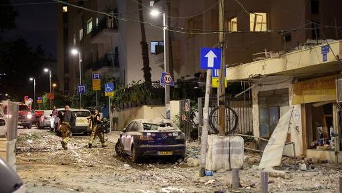 Members of the Israeli security forces walk along a debris-strewn street in Tel Aviv, after it was hit by a rocket fired by Palestinian militants from the Gaza Strip on October 7, 2023. Palestinian militant group Hamas launched a surprise large-scale attack against Israel on October 7, firing thousands of rockets from Gaza and sending fighters to kill or abduct people as Israel retaliated with devastating air strikes. (Photo by JACK GUEZ / AFP)