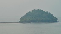 Wisatawan berjalan menuju Pulau Pisang Ketek yang berselimut kabut asap di Pantai Air Manis, Padang, Sumatera Barat. 