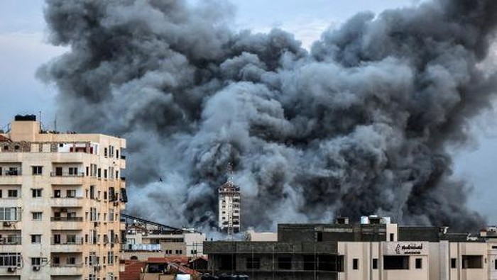 EDITORS NOTE: Graphic content / People standing on a rooftop watch as a ball of fire and smoke rises above a building in Gaza City on October 7, 2023 during an Israeli air strike that hit the Palestine Tower building. At least 70 people were reported killed in Israel, while Gaza authorities released a death toll of 198 in the bloodiest escalation in the wider conflict since May 2021, with hundreds more wounded on both sides. (Photo by MAHMUD HAMS / AFP)