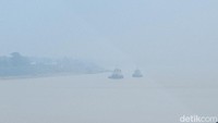 Terlihat dari kejauhan dua kapal berada di tengah jalur sungai Batanghari Jambi saat diselimuti kabut asap (Foto: Ferdi Al Munanda)