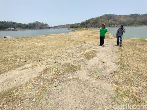 Bekas jalan aspal terlihat di tengah Waduk Sermo, Kulon Progo, yang surut debit airnya, Senin (9/10/2023).