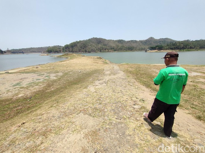 Bekas jalan aspal terlihat di tengah Waduk Sermo, Kulon Progo, yang surut debit airnya, Senin (9/10/2023).
