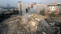 Warga Palestina memeriksa reruntuhan Menara Watan, yang hancur akibat serangan Israel, di Kota Gaza. REUTERS/Mohammed Salem