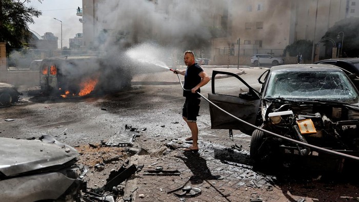 An emergency personnel works to extinguish fire after rockets launched from the Gaza Strip, as seen from the city of Ashkelon, Israel October 7, 2023. REUTERS/Amir Cohen