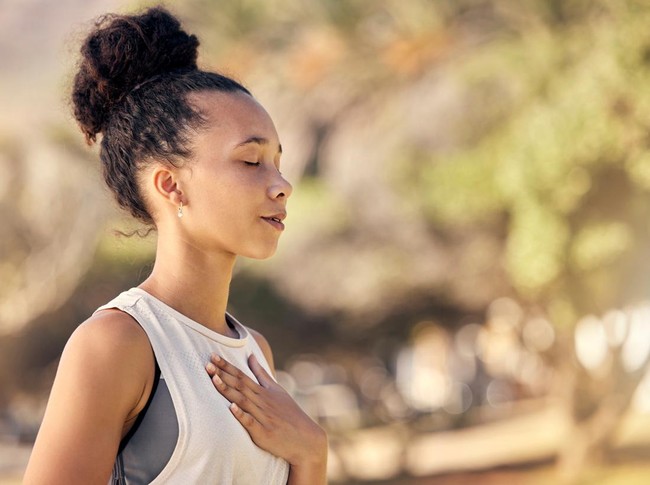 Black woman, breath and hand on chest, for meditation and wellness being peaceful to relax. Bokeh, African American female and lady outdoor, in nature and being calm for breathing exercise and health